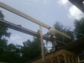 Carpenter setting a ridge beam over a new addition frame — Ice Dam Removal by Roofing Brothers in Manton