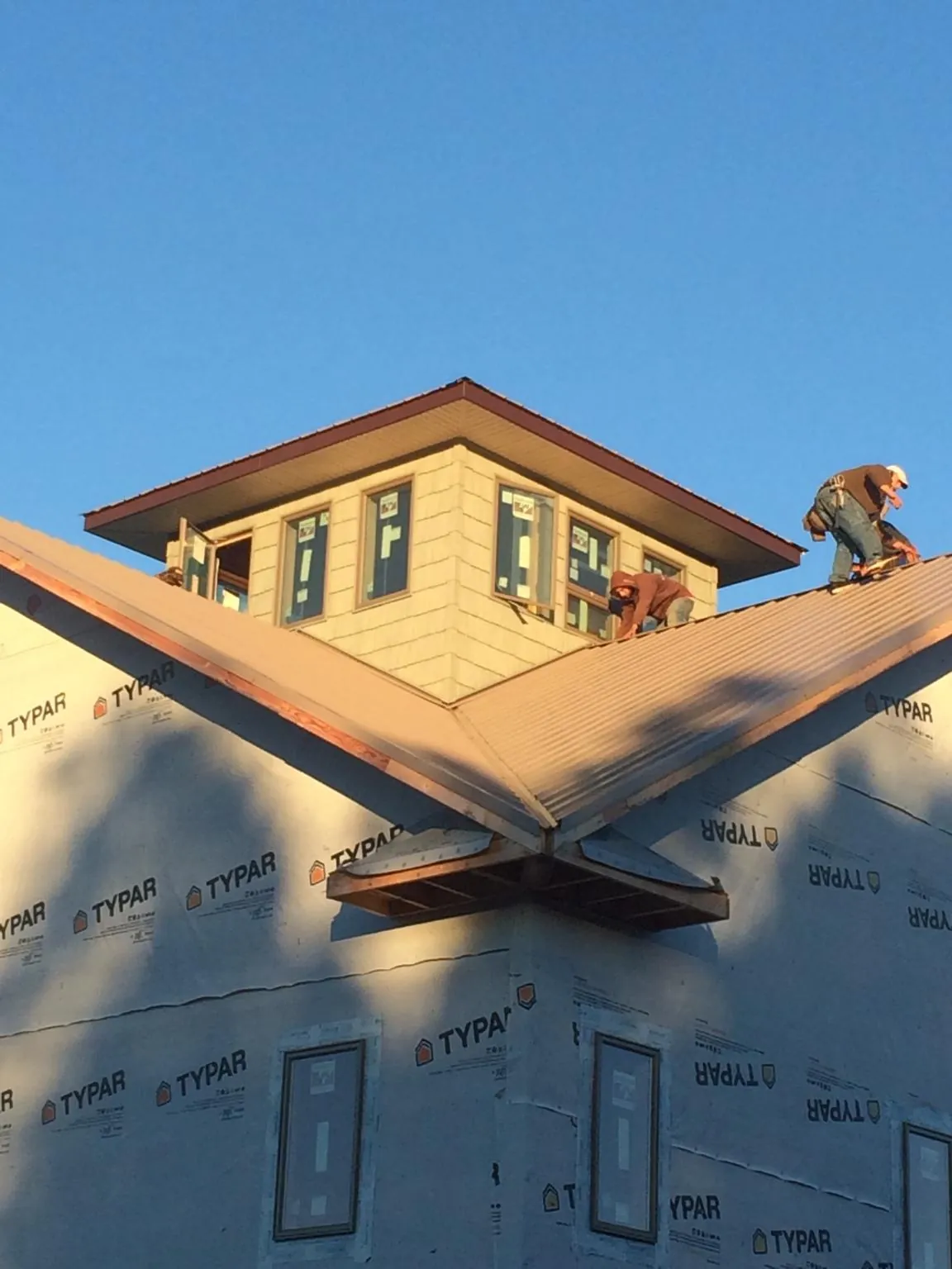 Roofers working around a rooftop cupola on a new metal roof at sunset — Roof Waterproofing in Manton by Roofing Brothers
